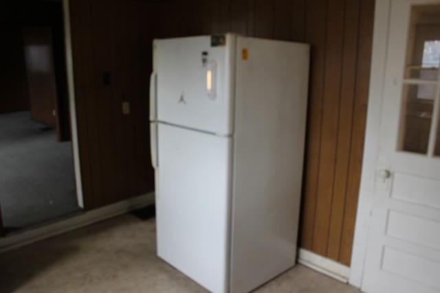 kitchen with wood walls and freestanding refrigerator