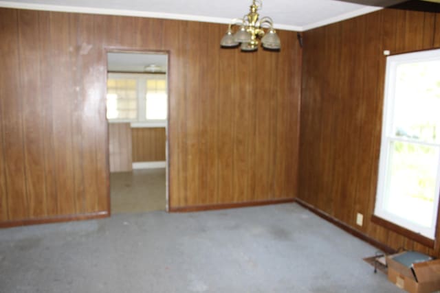 empty room with an inviting chandelier and wooden walls
