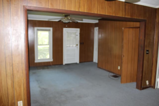 spare room featuring carpet flooring, a ceiling fan, and wood walls