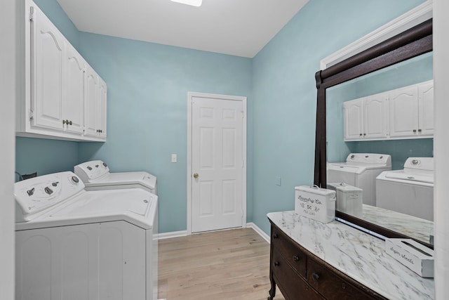 washroom featuring cabinets, separate washer and dryer, and light hardwood / wood-style floors