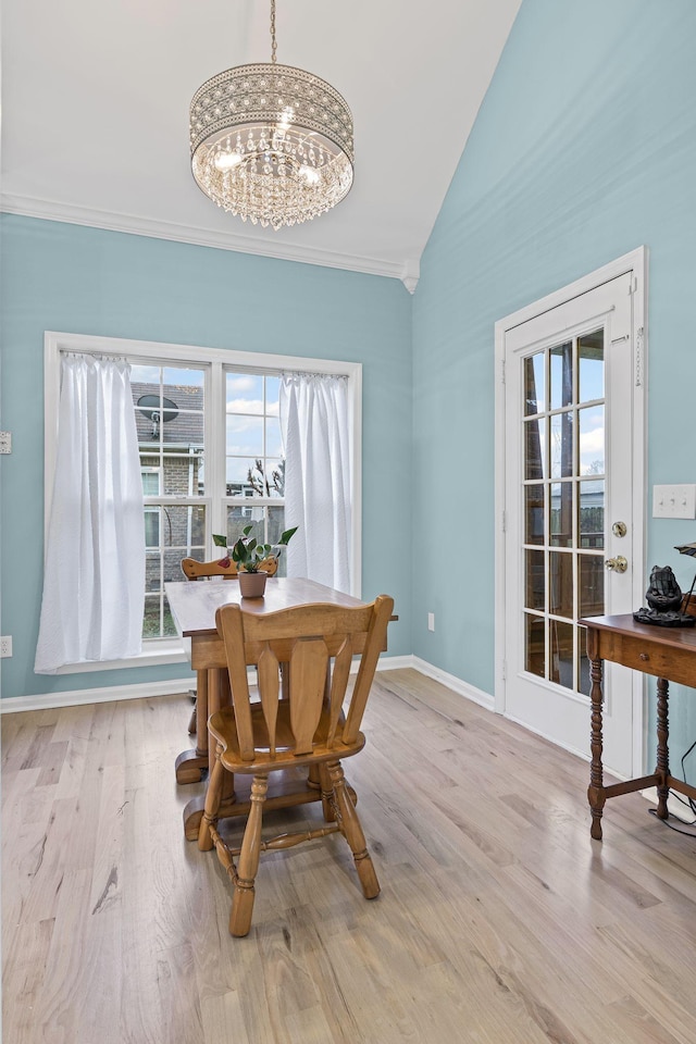 dining space with light hardwood / wood-style flooring, vaulted ceiling, and a chandelier