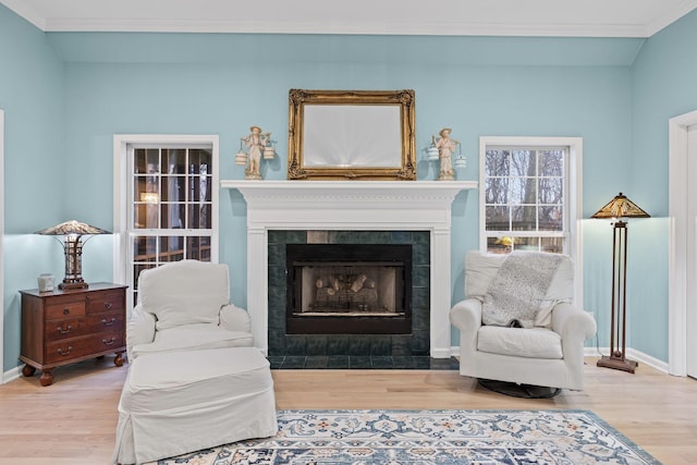 sitting room featuring crown molding, a tile fireplace, and light wood-type flooring