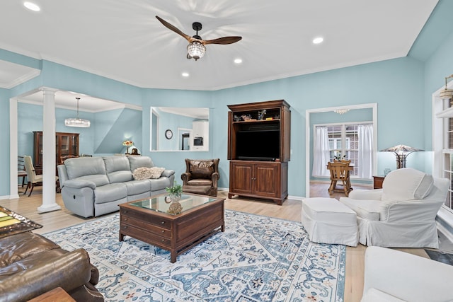 living room with decorative columns, ceiling fan, ornamental molding, and light wood-type flooring