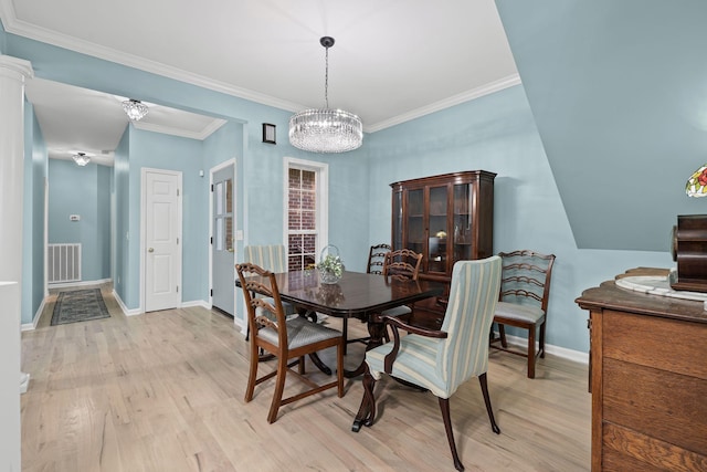 dining area with crown molding, an inviting chandelier, and light hardwood / wood-style floors