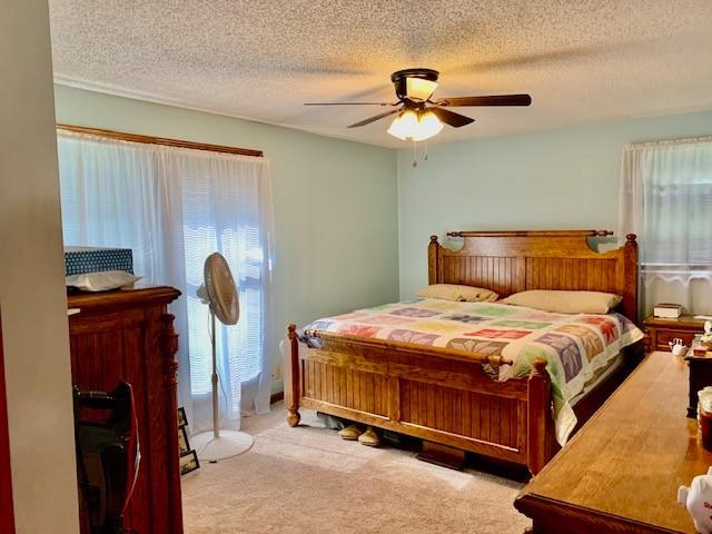 bedroom with light carpet, a textured ceiling, and ceiling fan