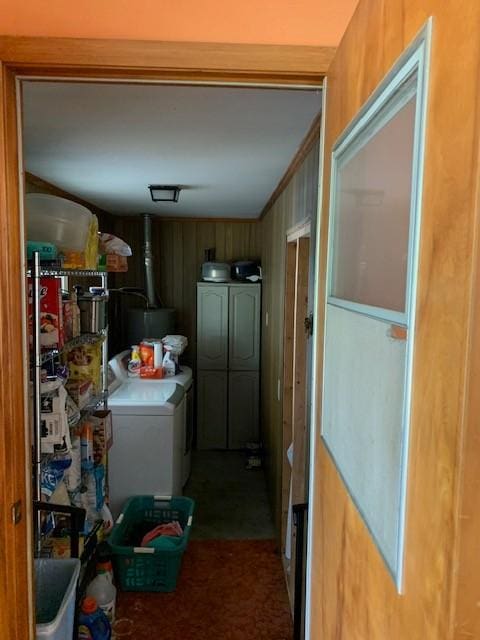 laundry room with wooden walls, washer and clothes dryer, and water heater