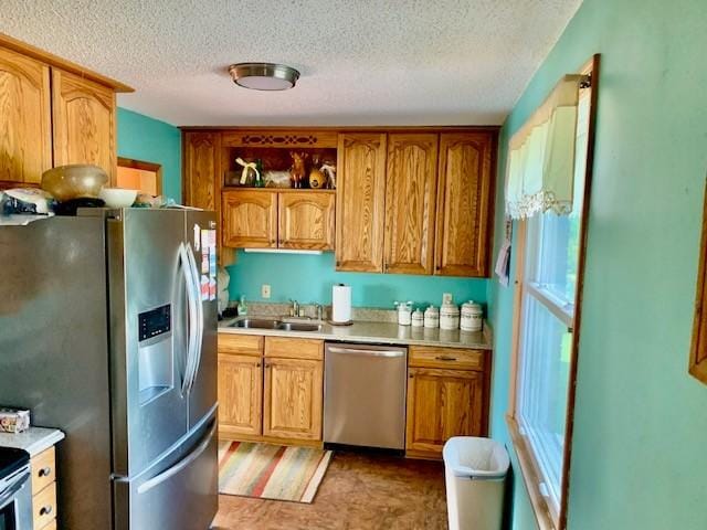 kitchen with appliances with stainless steel finishes, sink, and a textured ceiling