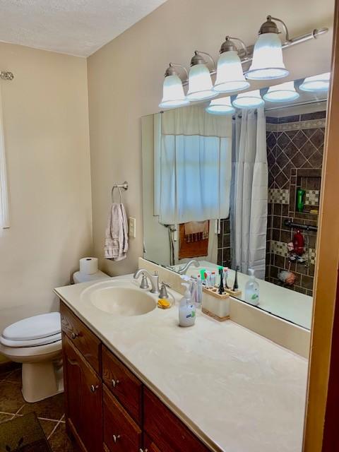 bathroom featuring vanity, a textured ceiling, a shower with curtain, tile patterned floors, and toilet