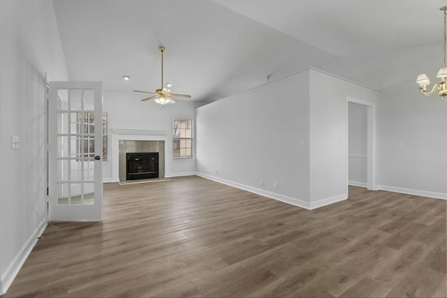 unfurnished living room featuring vaulted ceiling, a fireplace, ceiling fan with notable chandelier, and hardwood / wood-style floors