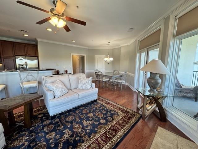 living room featuring ornamental molding, dark hardwood / wood-style floors, and ceiling fan with notable chandelier