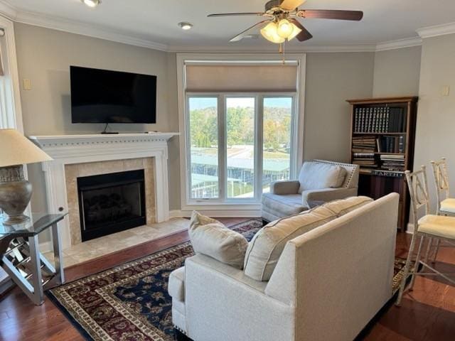 living room featuring crown molding, ceiling fan, wood-type flooring, and a fireplace