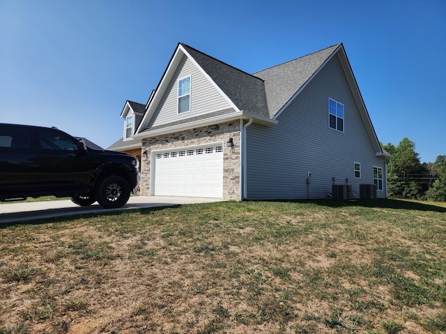 view of side of home with central AC, a garage, and a yard