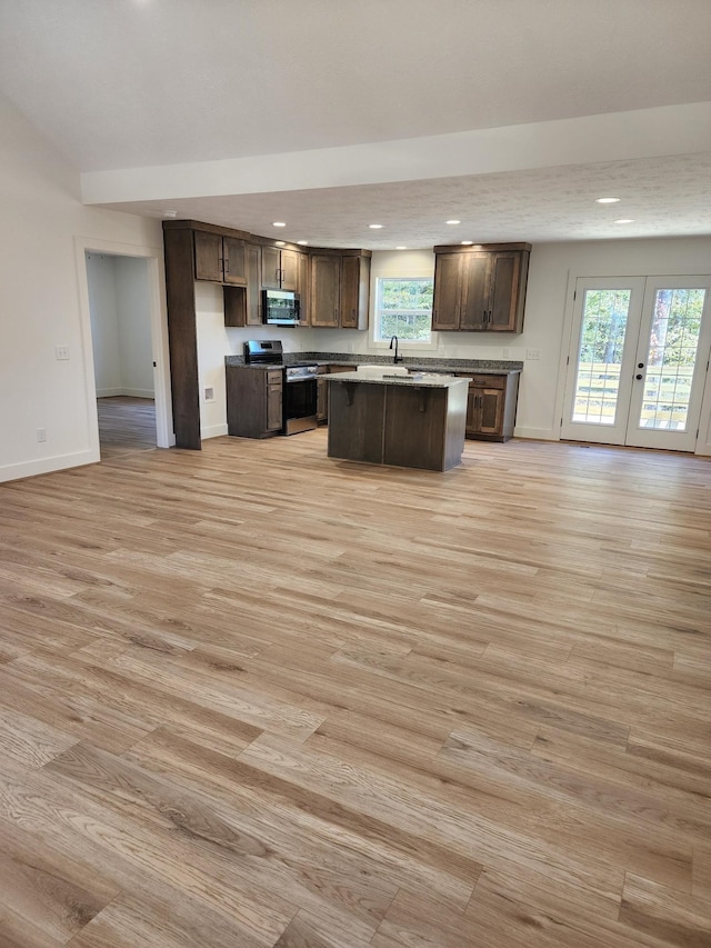 kitchen featuring appliances with stainless steel finishes, a center island, dark brown cabinets, and light wood-type flooring