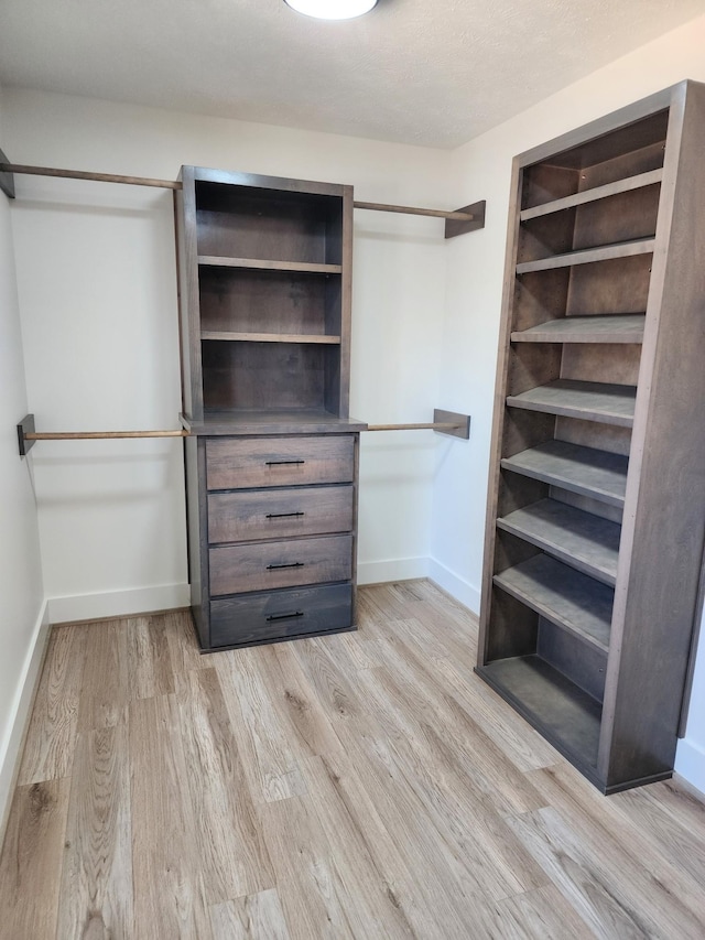 walk in closet with light hardwood / wood-style flooring