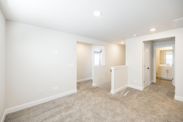 spare room featuring sink and light carpet