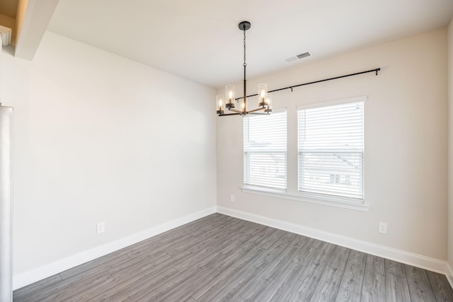 empty room featuring hardwood / wood-style floors and a chandelier