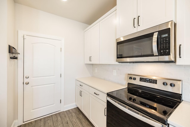 kitchen with white cabinetry, stainless steel appliances, dark hardwood / wood-style floors, and tasteful backsplash