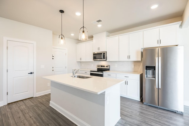 kitchen with sink, white cabinetry, decorative light fixtures, appliances with stainless steel finishes, and an island with sink