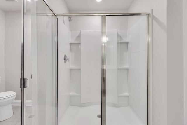 bathroom with tile patterned floors, toilet, and a shower with door