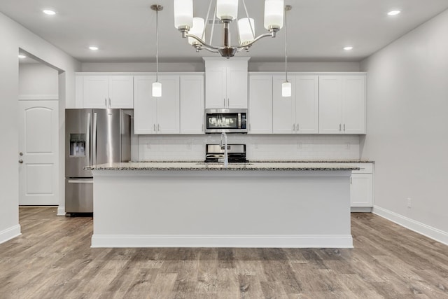 kitchen with stainless steel appliances, decorative light fixtures, and white cabinets