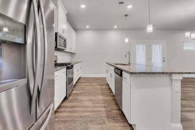 kitchen featuring sink, appliances with stainless steel finishes, a kitchen island with sink, hanging light fixtures, and white cabinets