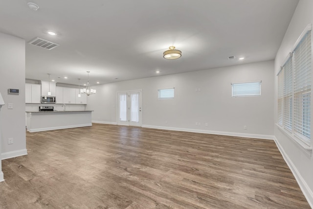 unfurnished living room with hardwood / wood-style flooring, sink, and a notable chandelier