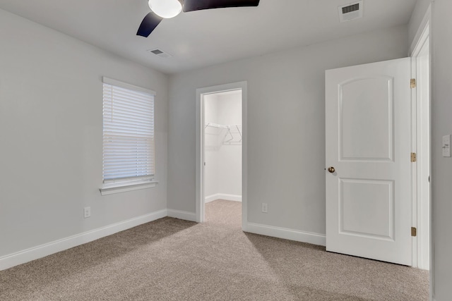 unfurnished bedroom featuring ceiling fan, light colored carpet, a spacious closet, and a closet