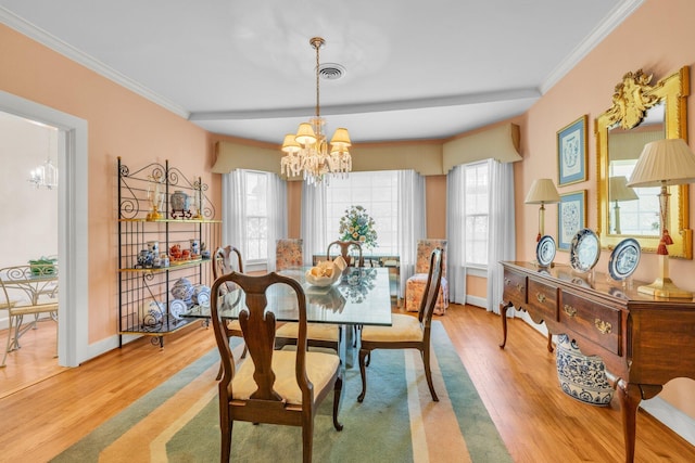 dining space with light hardwood / wood-style flooring, ornamental molding, and a chandelier