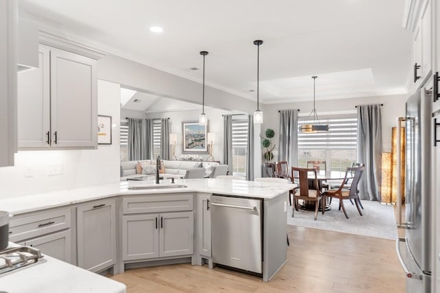 kitchen with stainless steel appliances, hanging light fixtures, sink, and kitchen peninsula