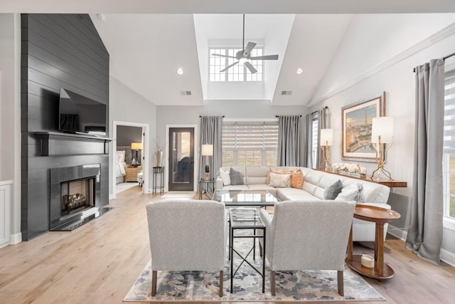 living room featuring ceiling fan, a fireplace, high vaulted ceiling, and light hardwood / wood-style flooring