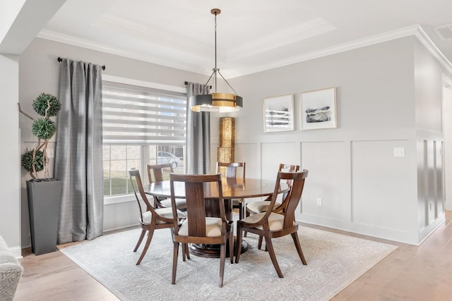 dining room featuring crown molding, a tray ceiling, and light hardwood / wood-style flooring