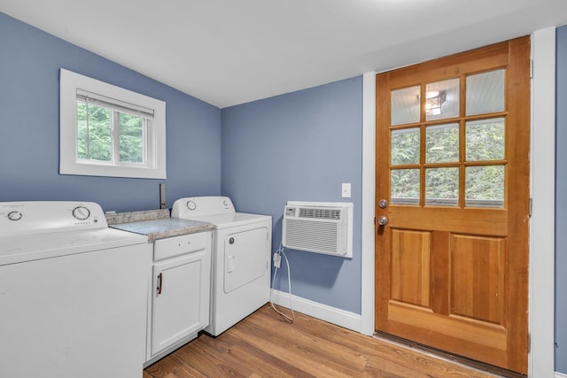 laundry area featuring cabinets, an AC wall unit, washer and dryer, and light hardwood / wood-style flooring