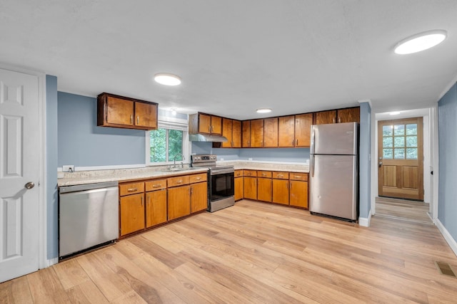 kitchen with sink, stainless steel appliances, and light hardwood / wood-style floors