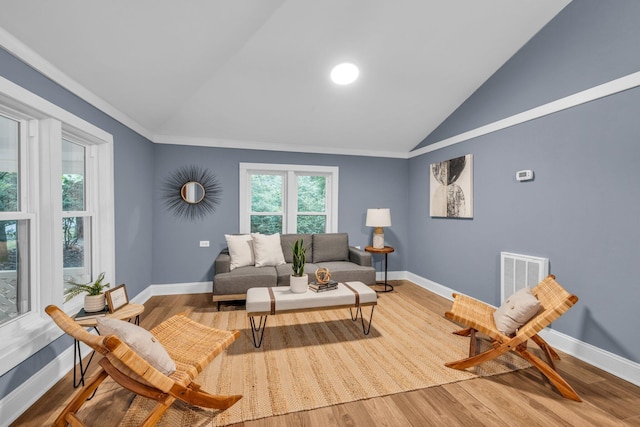 living room featuring hardwood / wood-style flooring, vaulted ceiling, and crown molding