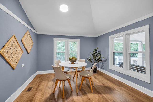 dining space featuring lofted ceiling, wood-type flooring, and plenty of natural light