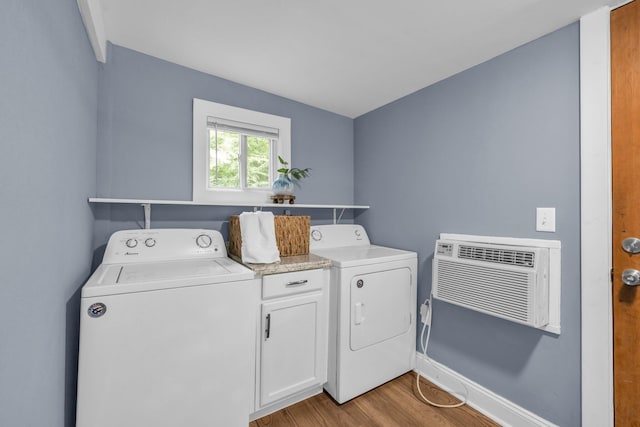 washroom with cabinets, light wood-type flooring, a wall mounted air conditioner, and washer and clothes dryer