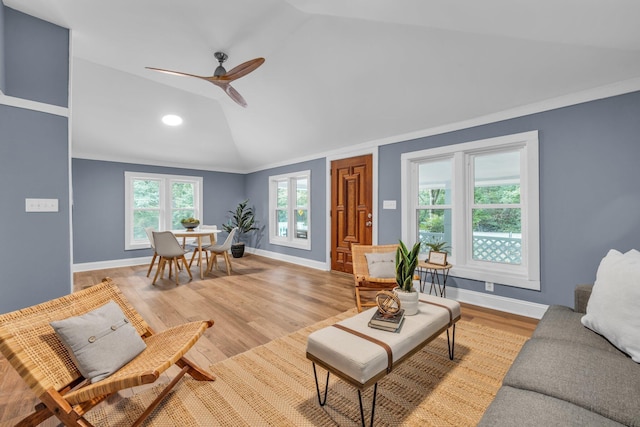 living room with ceiling fan, ornamental molding, lofted ceiling, and light hardwood / wood-style flooring