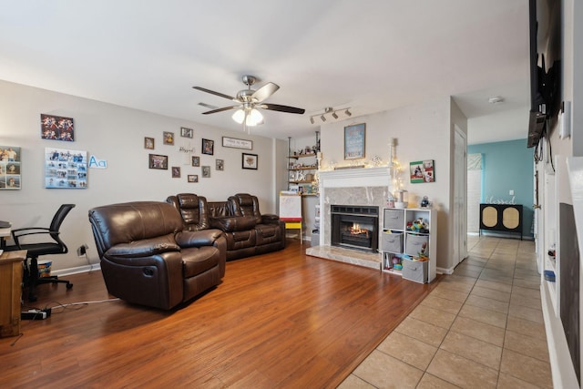 living room with ceiling fan, hardwood / wood-style floors, track lighting, and a high end fireplace