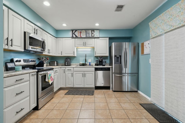 kitchen featuring stainless steel appliances, white cabinetry, sink, and light tile patterned flooring