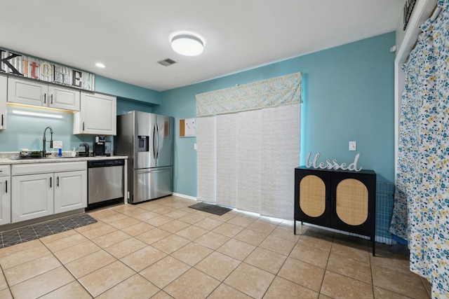 kitchen featuring white cabinetry, sink, light tile patterned floors, and appliances with stainless steel finishes