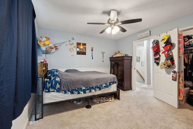 bedroom with ceiling fan, light colored carpet, a textured ceiling, and a closet