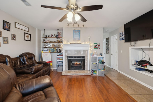 living room featuring hardwood / wood-style flooring, ceiling fan, and a high end fireplace