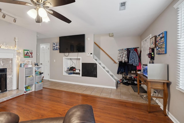 living room with wood-type flooring, ceiling fan, and a fireplace