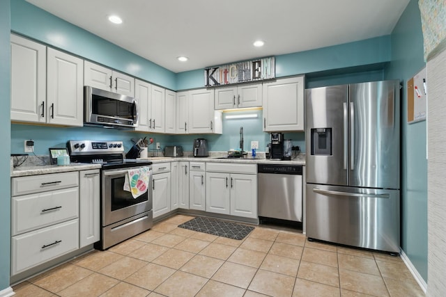 kitchen featuring sink, light tile patterned flooring, white cabinets, and appliances with stainless steel finishes