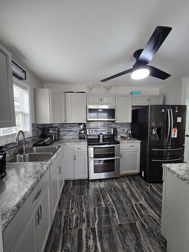 kitchen featuring ceiling fan, stainless steel appliances, sink, and backsplash