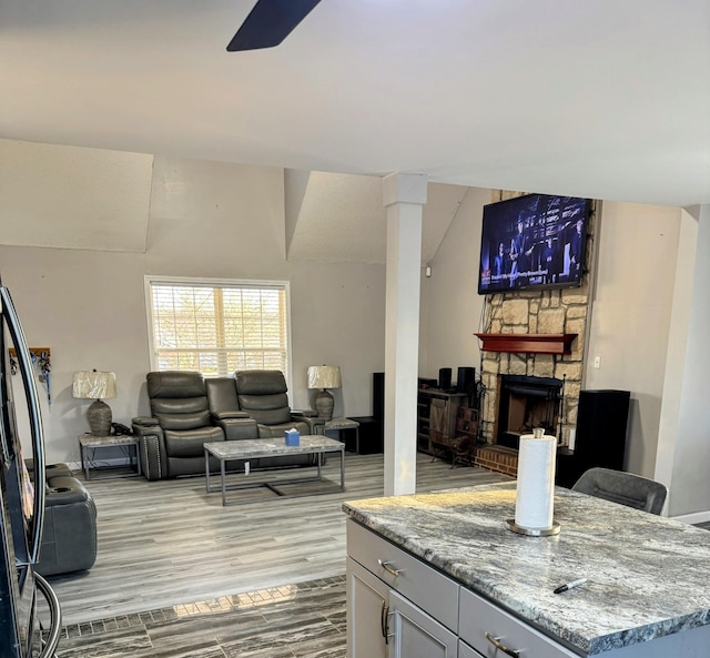 living room with lofted ceiling, ornate columns, light hardwood / wood-style flooring, ceiling fan, and a fireplace