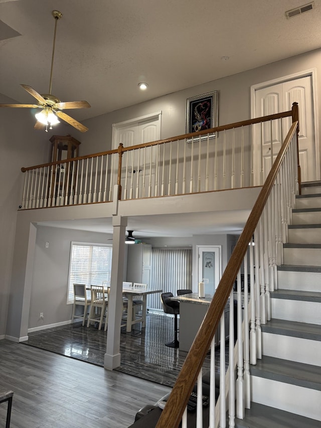 staircase featuring a high ceiling, wood-type flooring, and ceiling fan