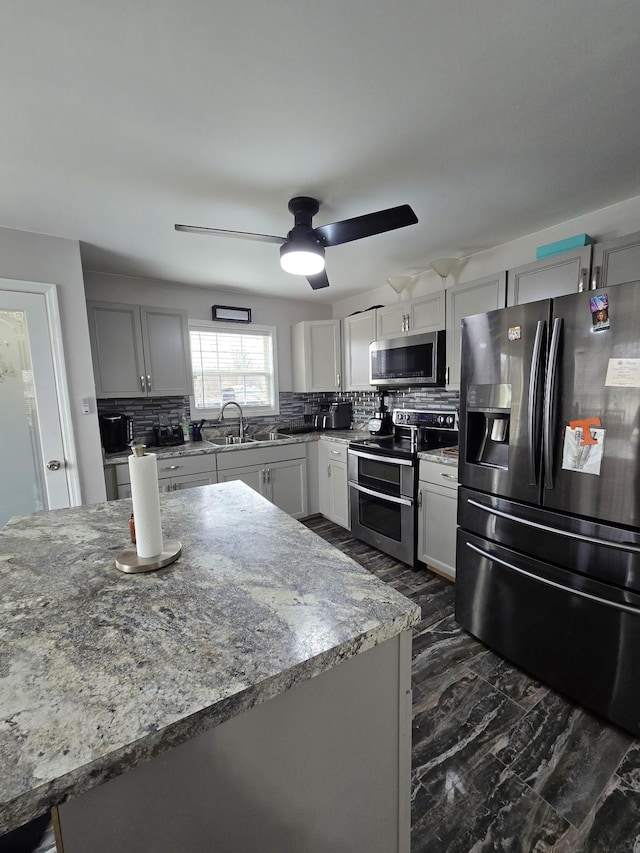 kitchen featuring tasteful backsplash, sink, ceiling fan, light stone counters, and stainless steel appliances