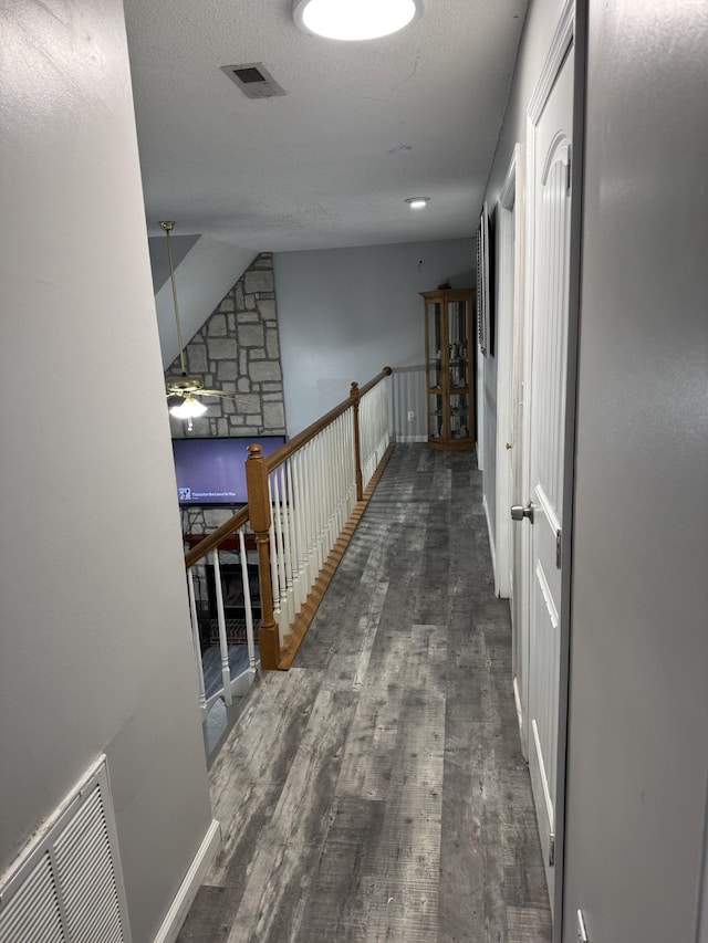 corridor with dark hardwood / wood-style floors and a textured ceiling