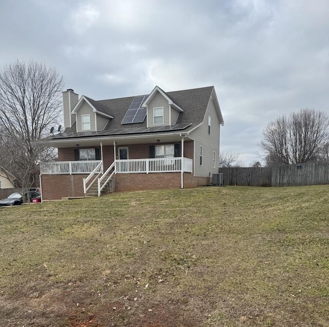 view of front of home with a porch, a front yard, central air condition unit, and solar panels